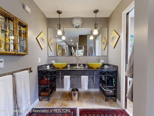 bathroom with baseboards, a sink, and double vanity