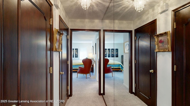 hall with an inviting chandelier and carpet flooring