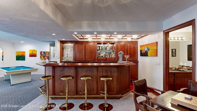 bar featuring carpet floors, a textured ceiling, a sink, and a community bar