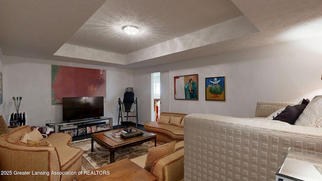 living area featuring a tray ceiling and a textured ceiling