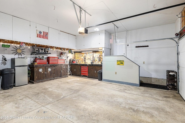garage featuring freestanding refrigerator, a garage door opener, and a workshop area