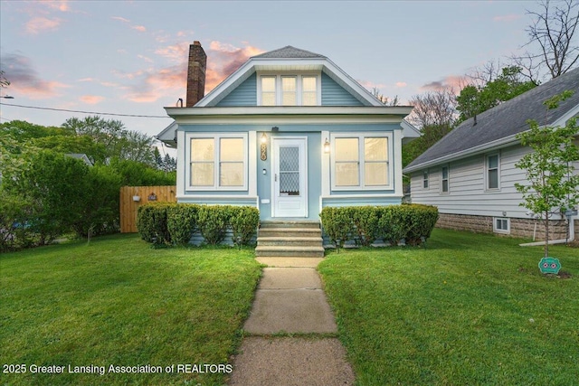 view of front of house with fence, a chimney, and a front yard