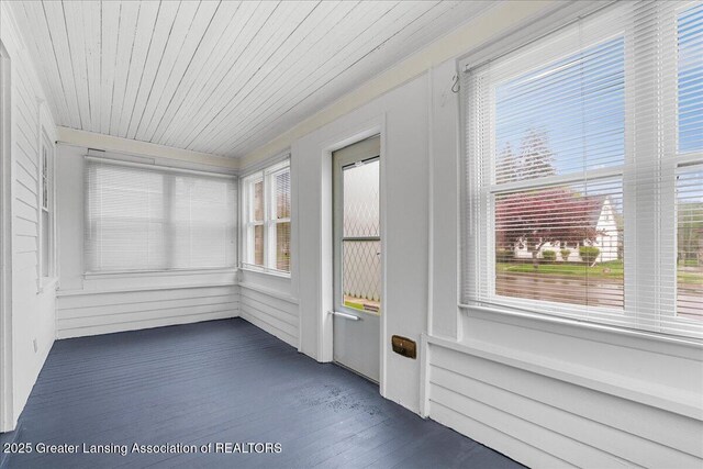 unfurnished sunroom with wooden ceiling, wood finished floors, and a wealth of natural light