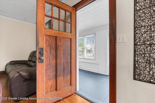 interior space featuring baseboards, ornamental molding, and wood finished floors