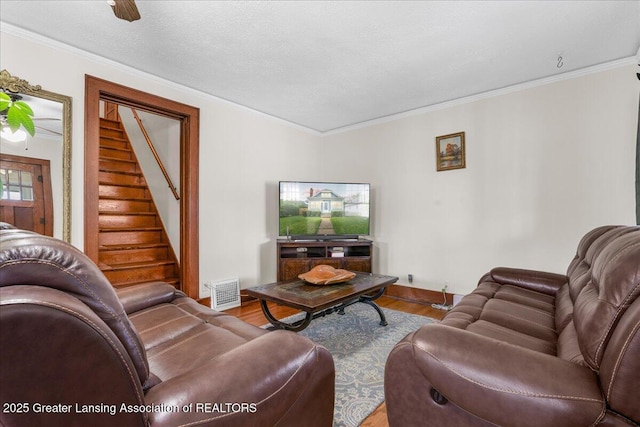 living room with crown molding, visible vents, wood finished floors, and stairway