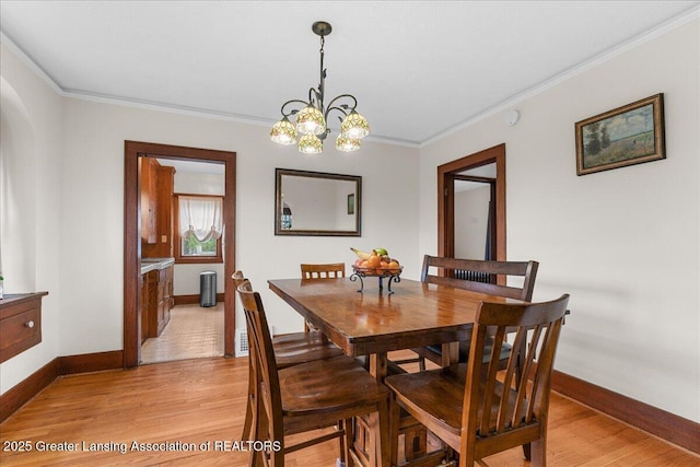 dining room with baseboards, light wood finished floors, crown molding, and a notable chandelier