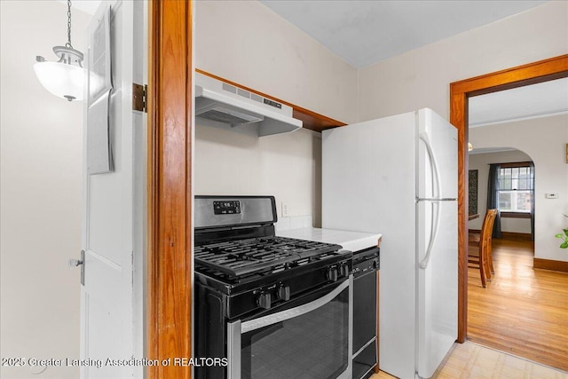 kitchen with arched walkways, stainless steel gas stove, under cabinet range hood, light floors, and black dishwasher