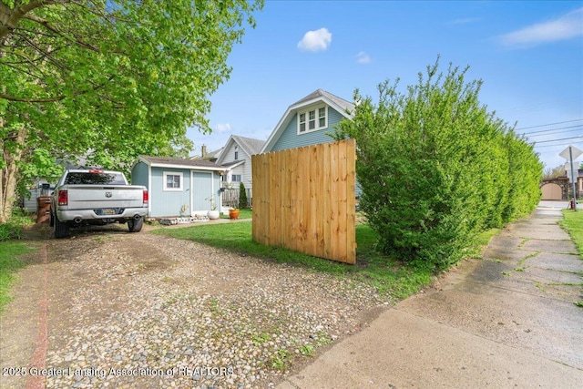 exterior space with a storage unit, an outdoor structure, dirt driveway, and fence