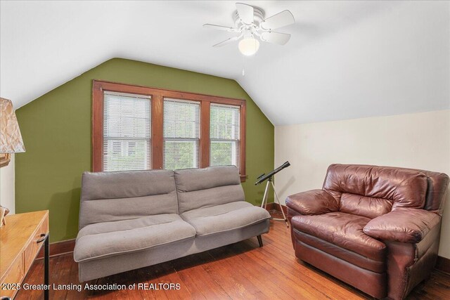 living room featuring baseboards, ceiling fan, vaulted ceiling, and wood finished floors