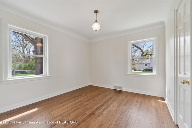 empty room featuring light wood-type flooring, baseboards, and visible vents