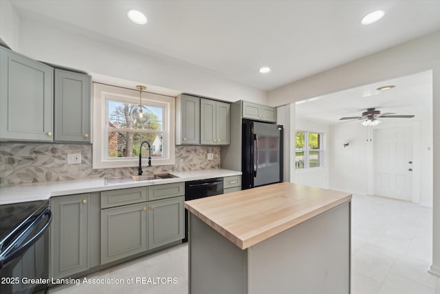 kitchen featuring a sink, wood counters, gray cabinets, decorative backsplash, and black appliances