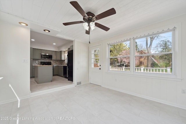 unfurnished living room with a healthy amount of sunlight, baseboards, ceiling fan, and visible vents