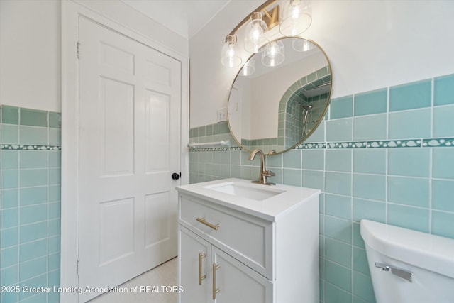 bathroom with toilet, tile walls, a wainscoted wall, and vanity