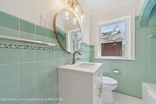 bathroom with vanity, toilet, tile walls, tile patterned floors, and a bath