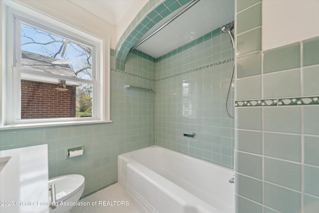 bathroom with toilet, tile patterned floors, tile walls, and bathtub / shower combination