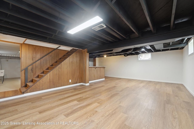 basement featuring baseboards, visible vents, wood finished floors, and stairway