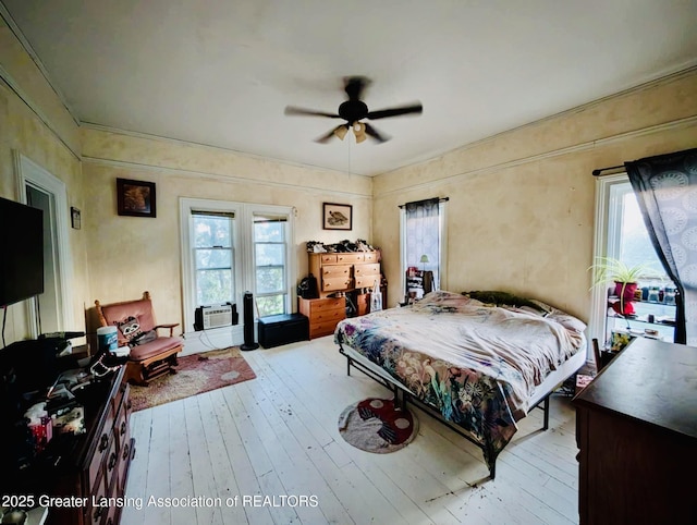 bedroom with multiple windows, wood-type flooring, ceiling fan, and cooling unit