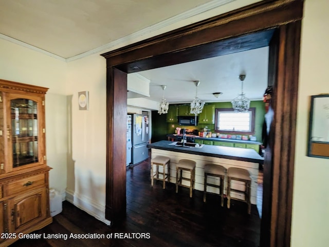 kitchen with black microwave, crown molding, a sink, freestanding refrigerator, and an inviting chandelier