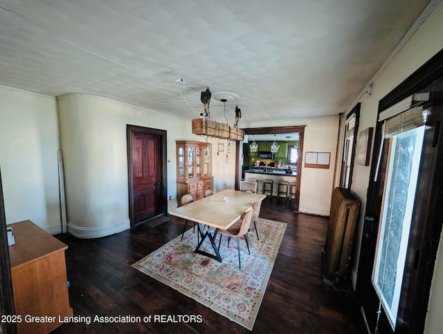 dining area with radiator, baseboards, ornamental molding, and hardwood / wood-style flooring