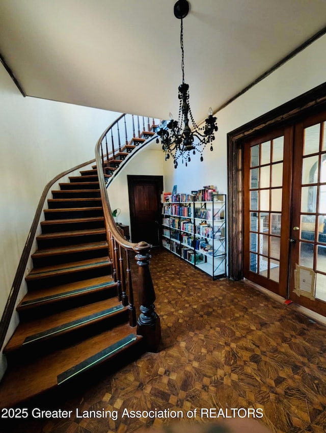 staircase with a notable chandelier and french doors