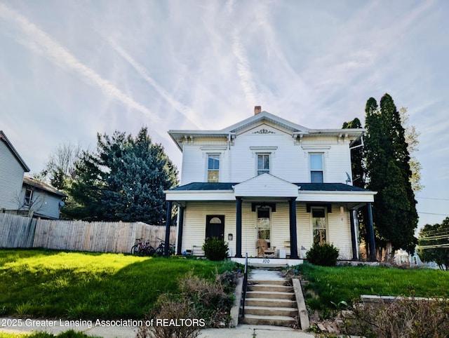 italianate home featuring a porch, a front lawn, fence, and a chimney