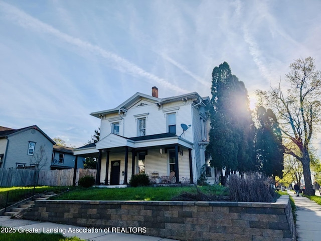 italianate home featuring fence, covered porch, and a chimney
