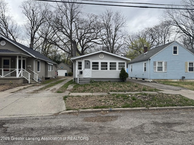 bungalow-style house featuring a garage, covered porch, an outbuilding, and concrete driveway