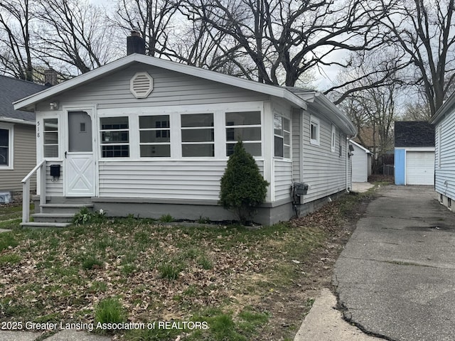 view of front facade featuring a detached garage, a chimney, and an outdoor structure