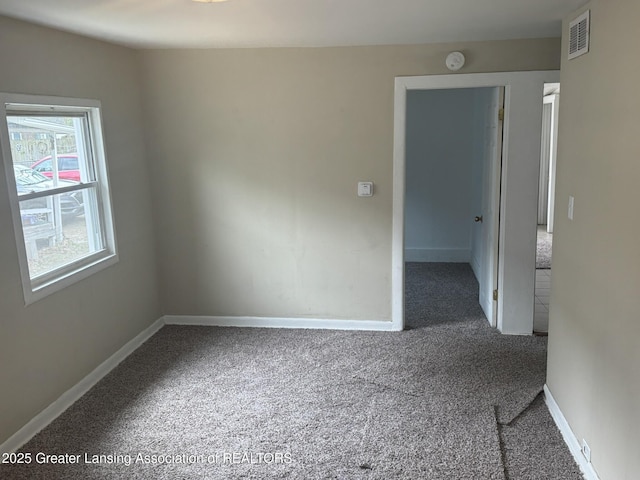 carpeted empty room featuring baseboards and visible vents