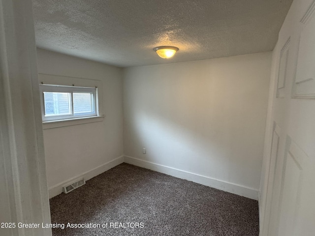 spare room featuring visible vents, a textured ceiling, dark carpet, and baseboards