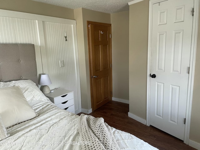 bedroom featuring baseboards, a textured ceiling, and dark wood-style flooring