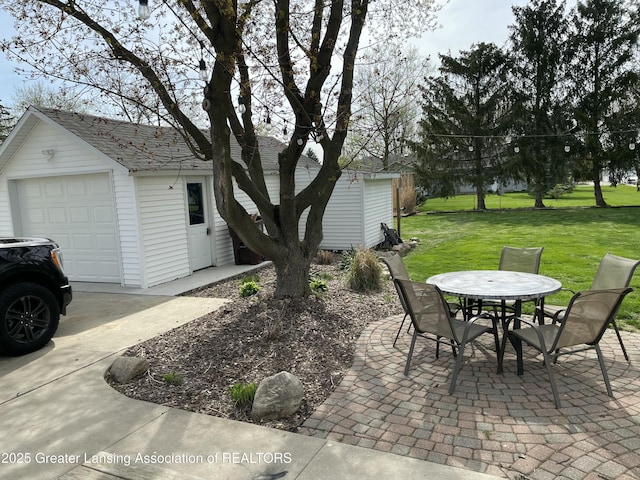 view of patio with a garage, outdoor dining space, and an outbuilding
