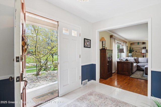 entrance foyer with visible vents, wainscoting, and tile patterned flooring