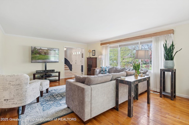 living room with baseboards, ornamental molding, and light wood-style flooring