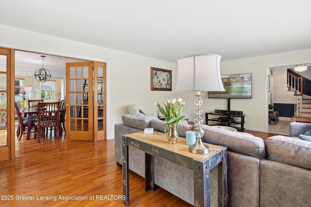 living area with crown molding, light wood finished floors, and a chandelier