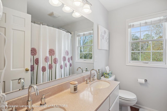 bathroom featuring double vanity, toilet, visible vents, and a sink