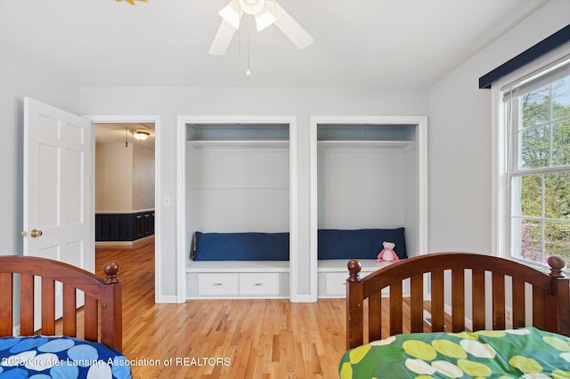 bedroom with ceiling fan, multiple closets, and light wood-type flooring