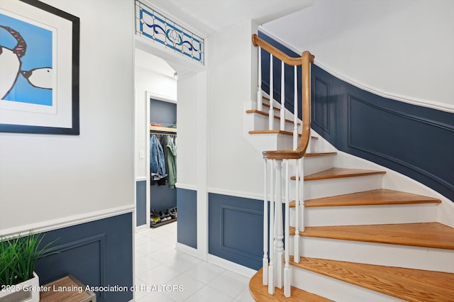 staircase featuring tile patterned floors and a wainscoted wall