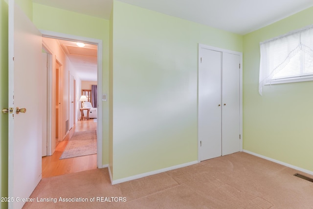 unfurnished bedroom featuring carpet floors, baseboards, visible vents, and multiple windows