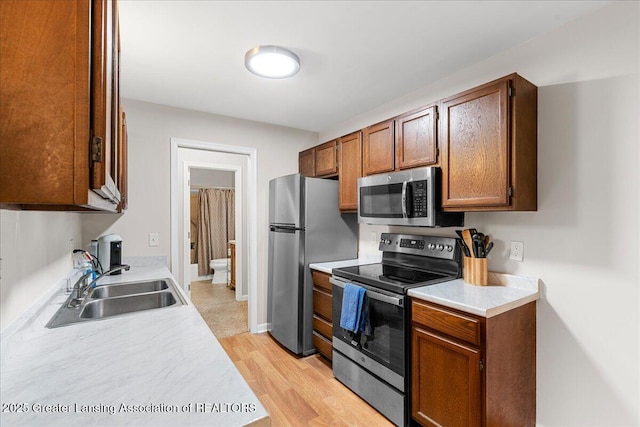 kitchen featuring a sink, light countertops, light wood-style floors, and stainless steel appliances