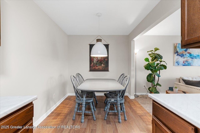 dining area featuring baseboards and light wood-style flooring