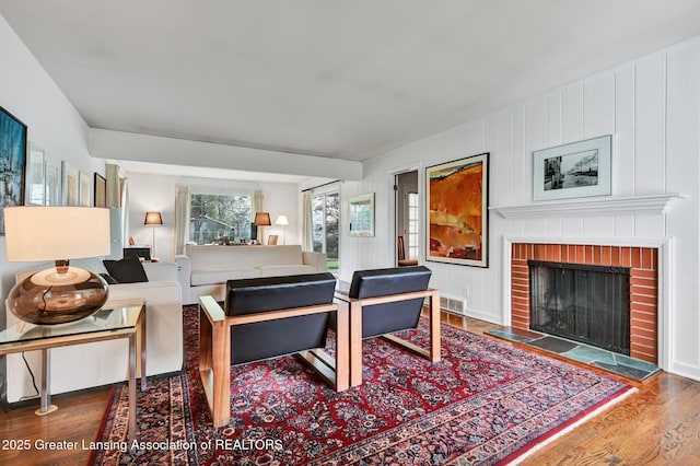 living area featuring visible vents, a brick fireplace, and wood finished floors