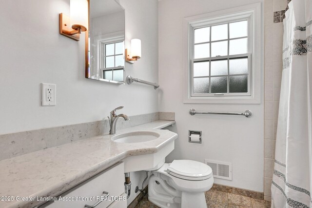 bathroom featuring toilet, visible vents, curtained shower, and a sink
