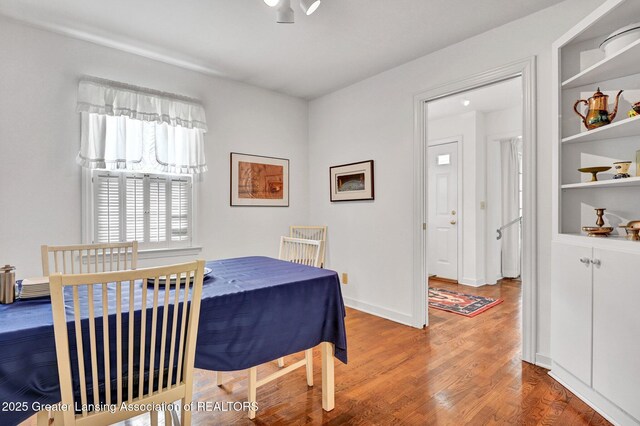 dining area with built in features, baseboards, and wood finished floors