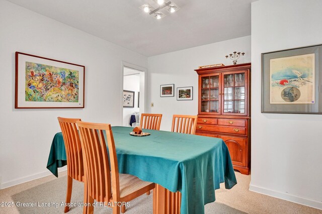 dining area with baseboards and light carpet