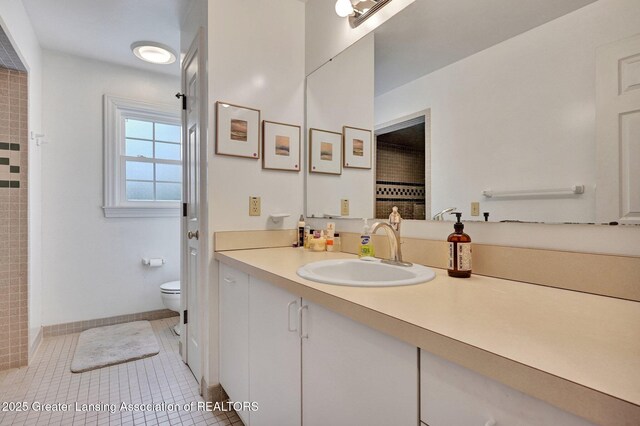full bath with a tile shower, vanity, toilet, tile patterned floors, and baseboards