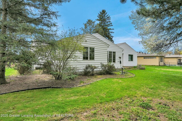 rear view of house with a yard and fence