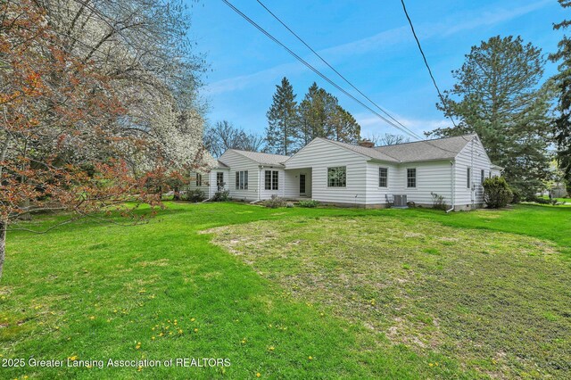 back of house featuring a yard, a chimney, and a shingled roof