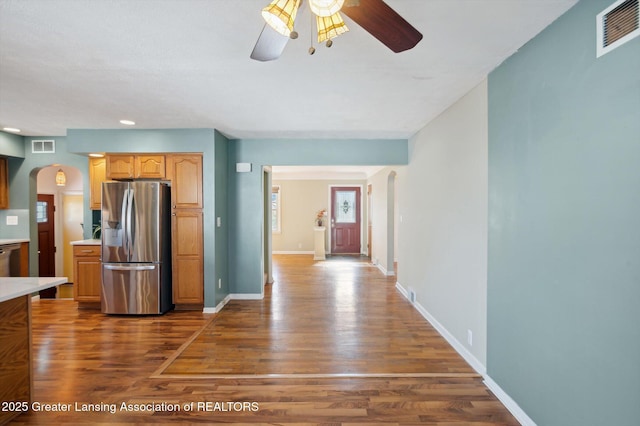 kitchen featuring visible vents, a ceiling fan, stainless steel refrigerator with ice dispenser, arched walkways, and dark wood finished floors