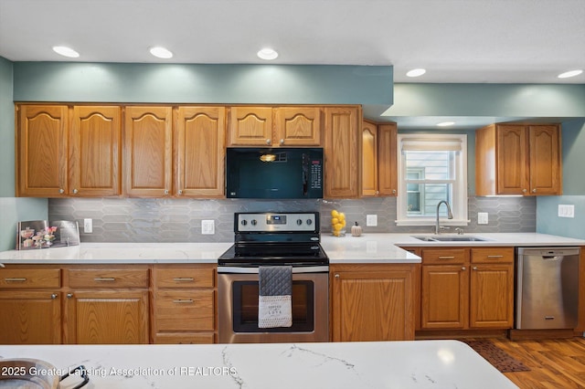 kitchen with dark wood-type flooring, light countertops, a sink, appliances with stainless steel finishes, and backsplash